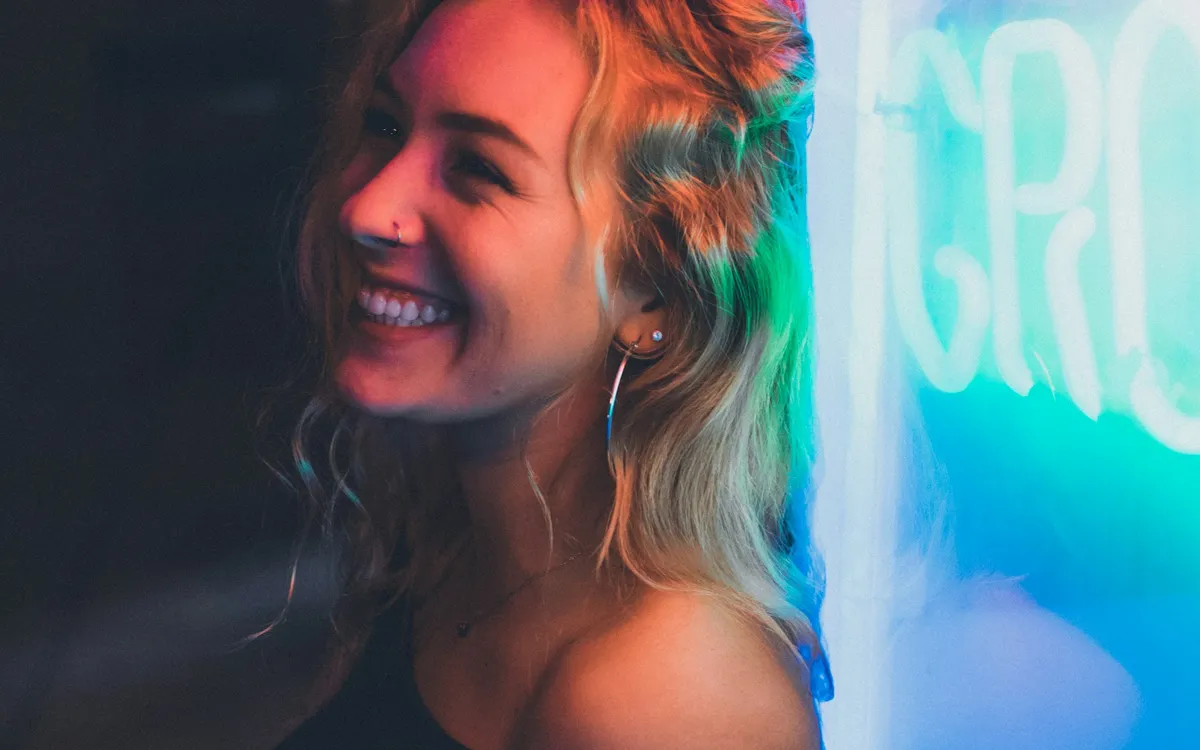 Mulher sorrindo iluminada por luzes coloridas