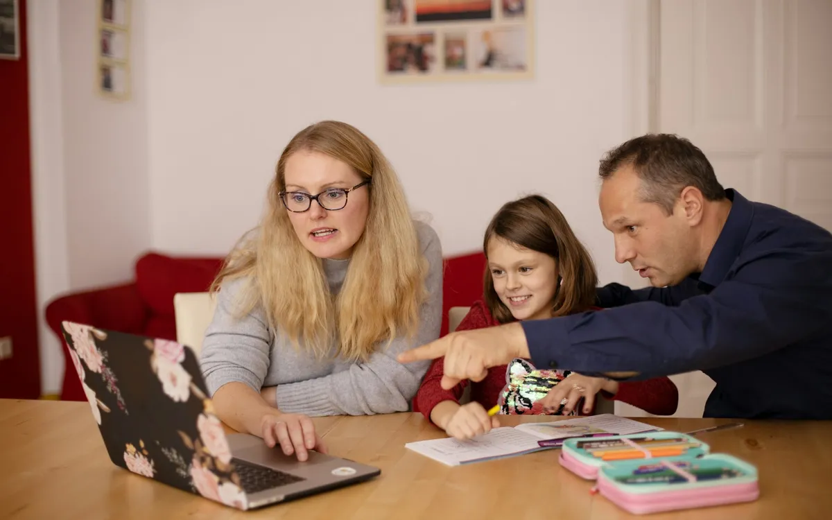 Casal ajudando uma criança com uma tarefa no computador