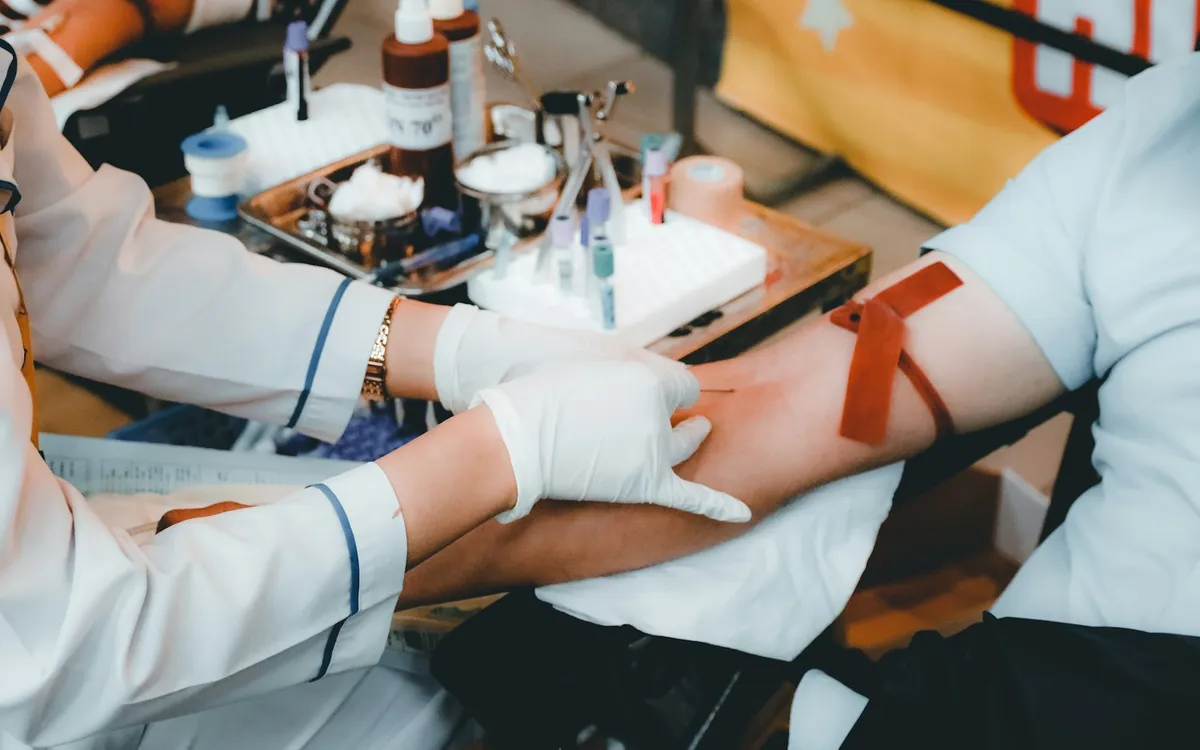 Profissional de saúde com luvas coletando sangue do braço de um paciente