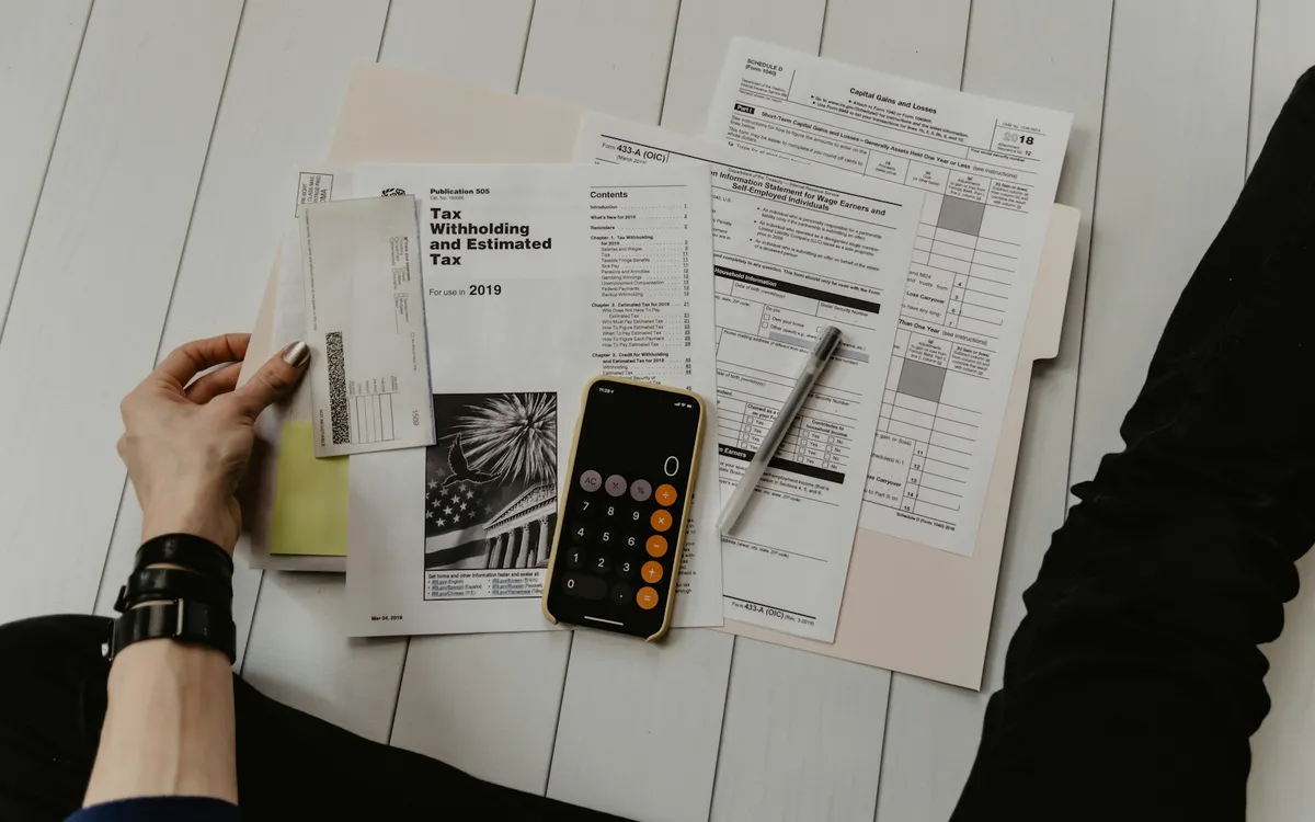 Pessoa revisando contas e documentos com uma calculadora