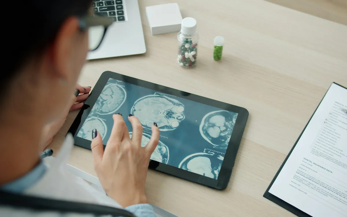Médica analisando imagens de ressonância magnética em um tablet sobre a mesa
