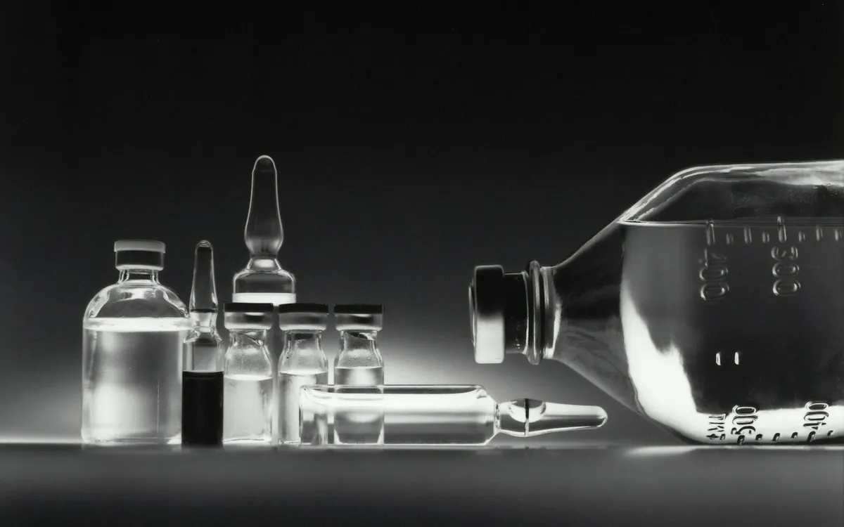 Frascos e ampolas de medicamento sobre uma superfície escura