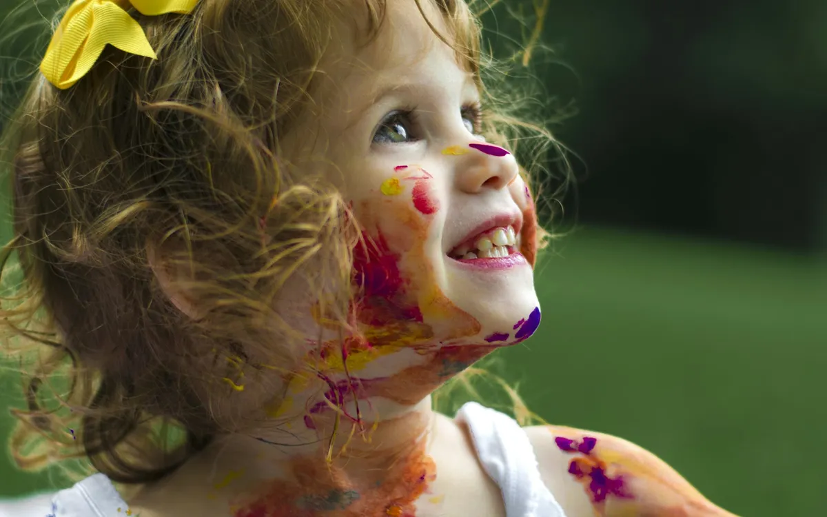 Menina sorrindo com o rosto pintado de cores