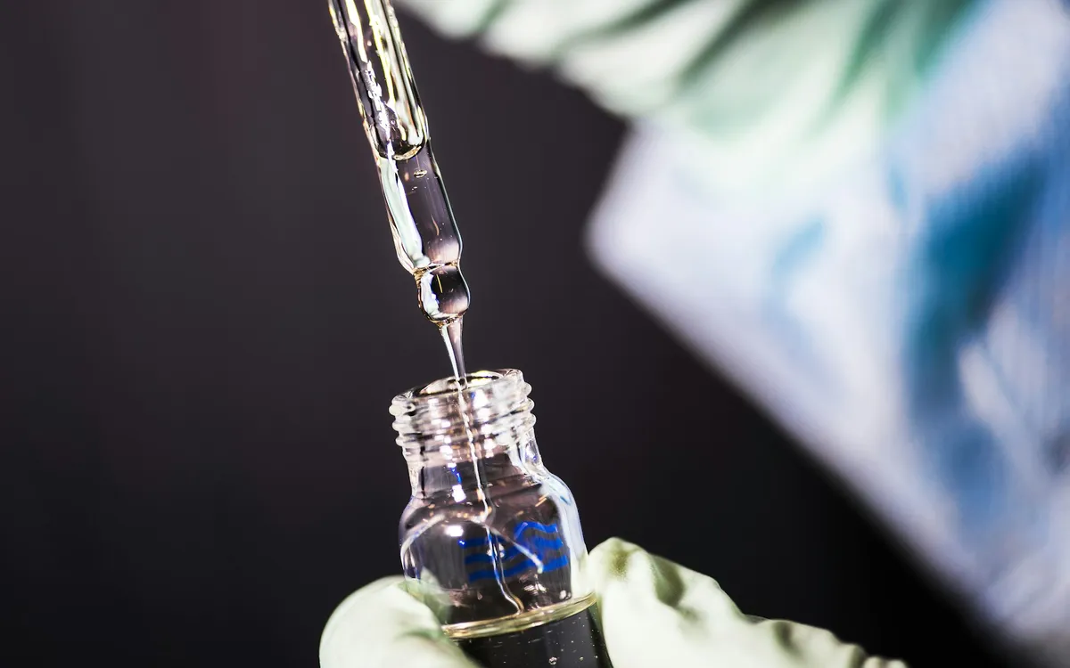 Pipeta pingando líquido em um frasco de laboratório