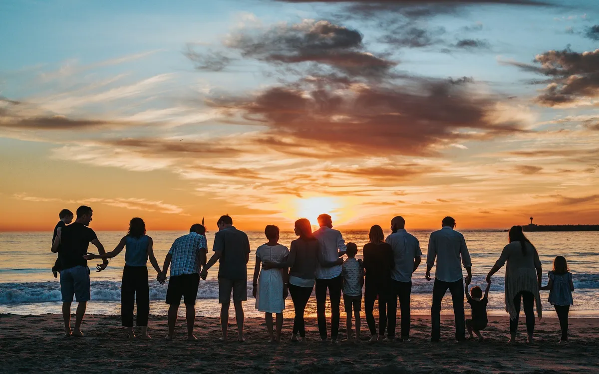 Família de várias gerações reunida na praia ao pôr do sol