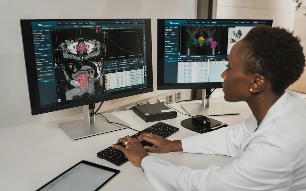 Profissional de saúde analisando imagens médicas em dois monitores