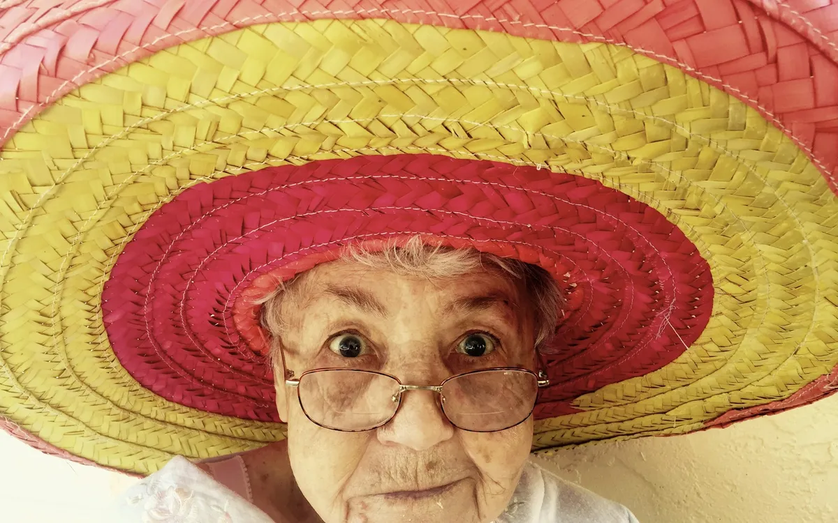 Senhora sorridente usando um chapéu colorido
