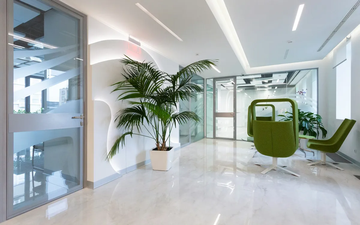 Recepção clara de uma clínica com poltronas verdes e plantas