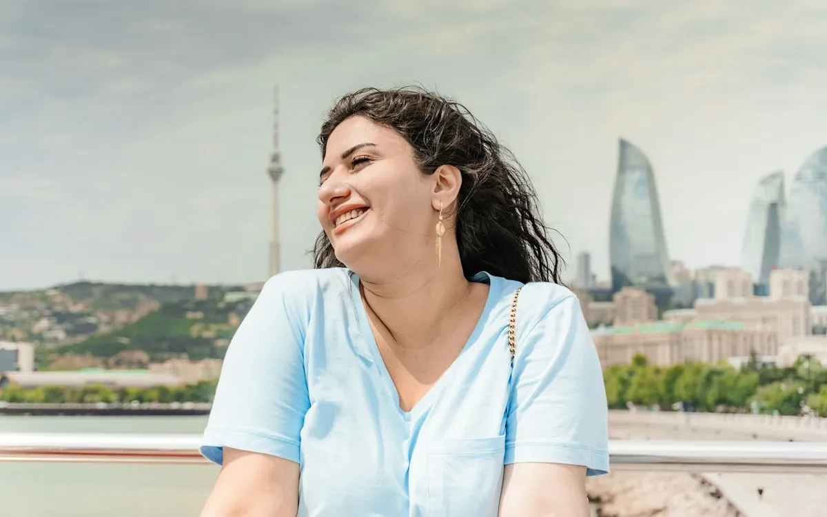 Jovem mulher sorrindo com prédios da cidade ao fundo
