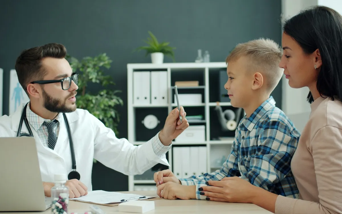 Médico examinando um menino com a mãe ao lado