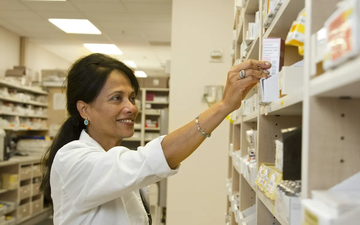 Farmacêutico pegando caixa de remédio na prateleira