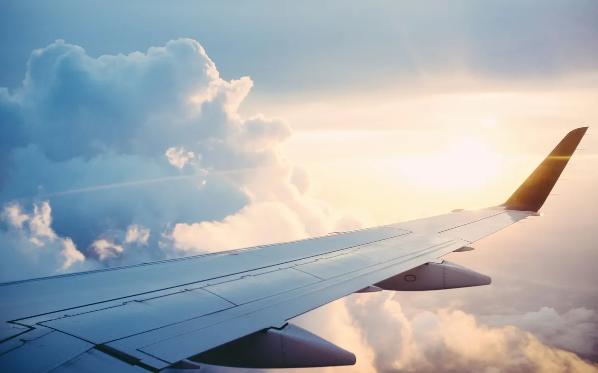 Asa de avião sobre as nuvens ao pôr do sol