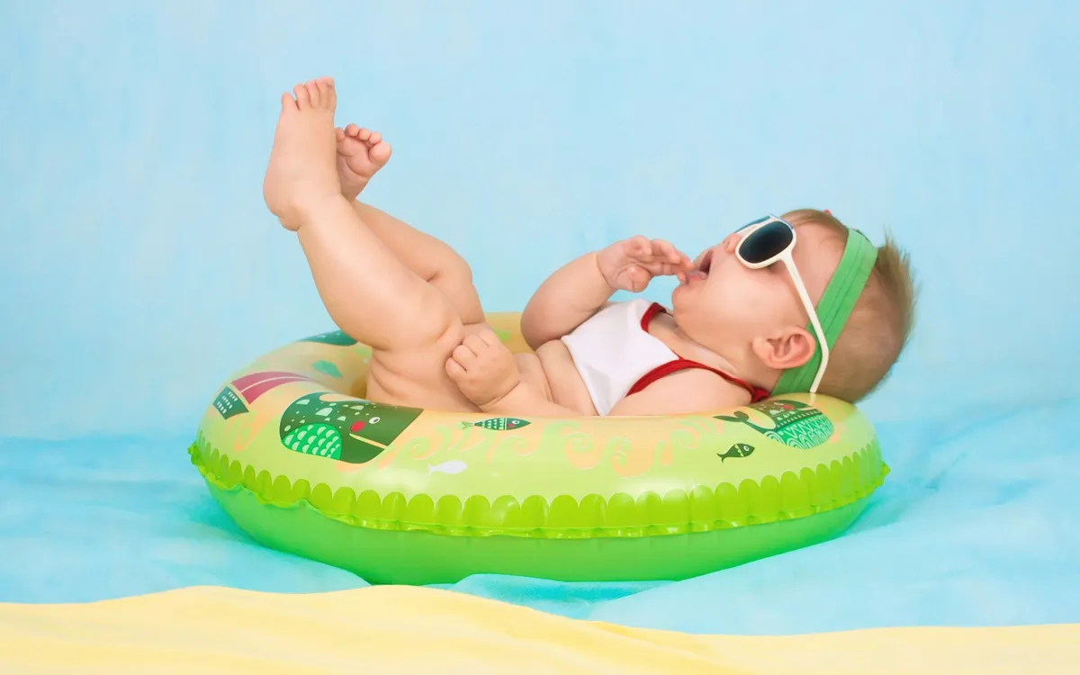 Bebê de óculos escuros deitado numa boia