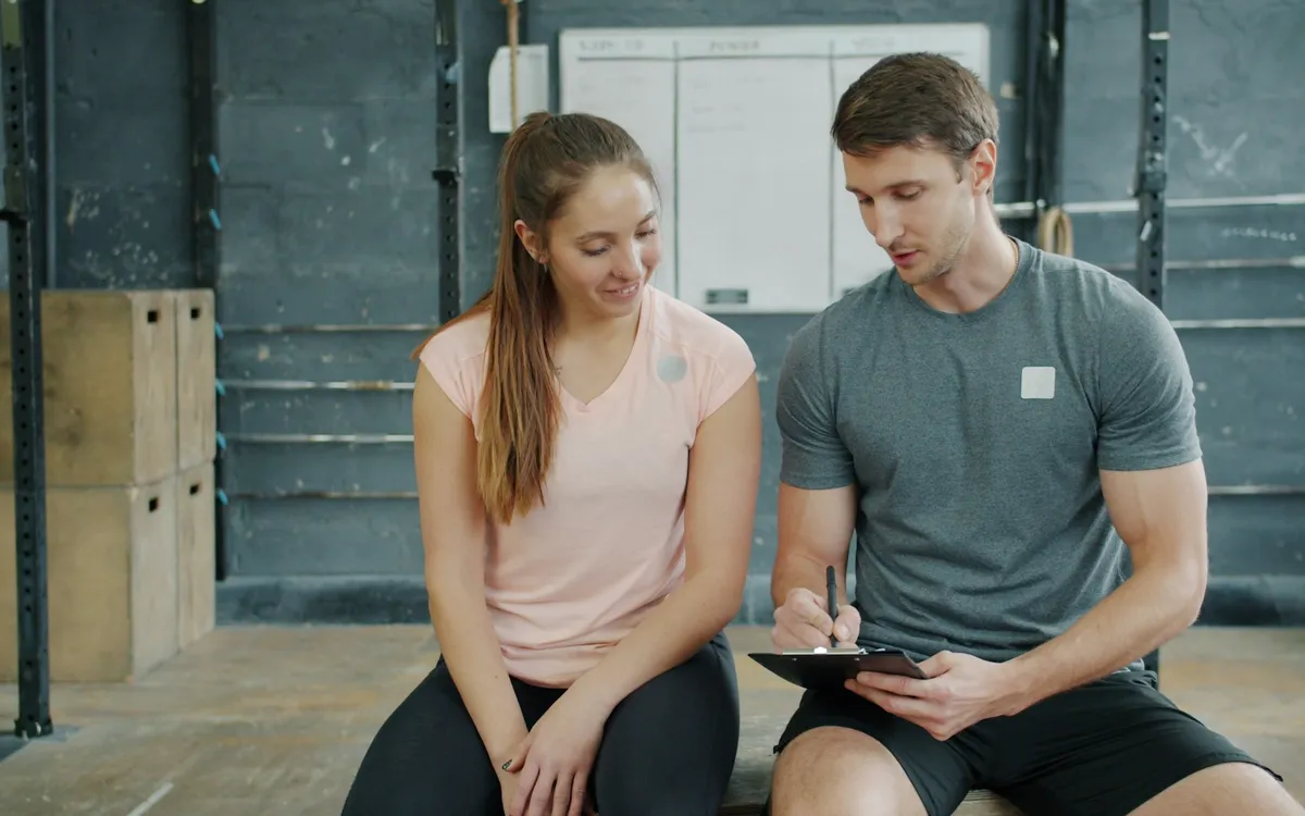 Personal trainer conversando com a aluna sobre o plano de treino na academia