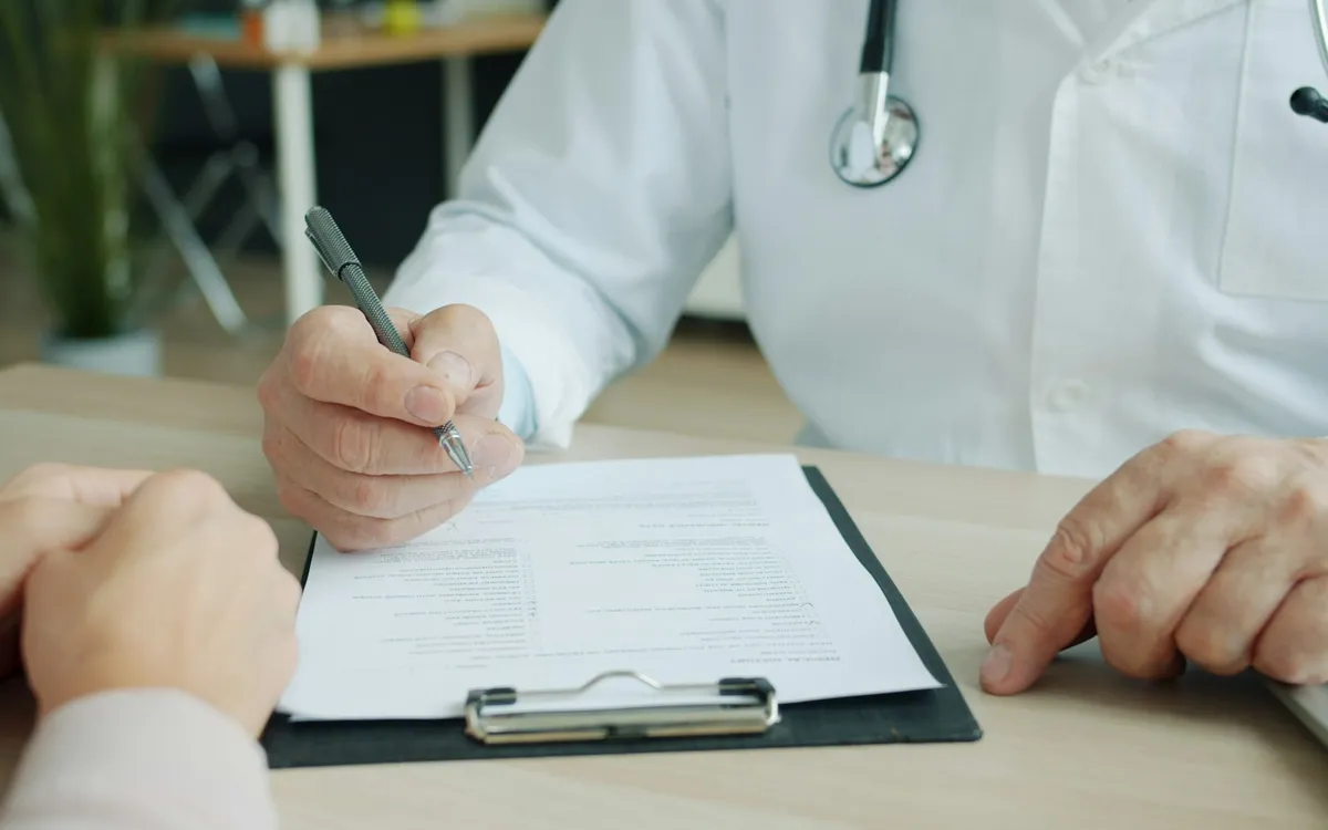 Médico escrevendo no prontuário durante a consulta