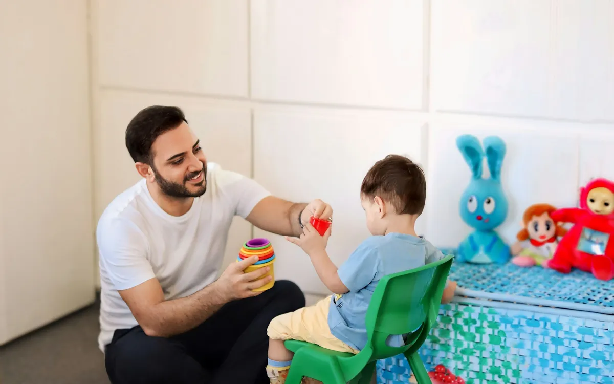 Profissional brincando com uma criança pequena em uma sala de atendimento