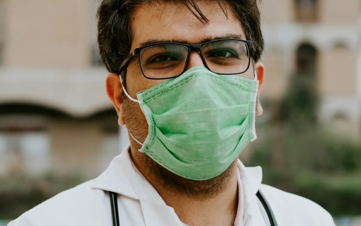 Médico de óculos e máscara cirúrgica com estetoscópio no pescoço