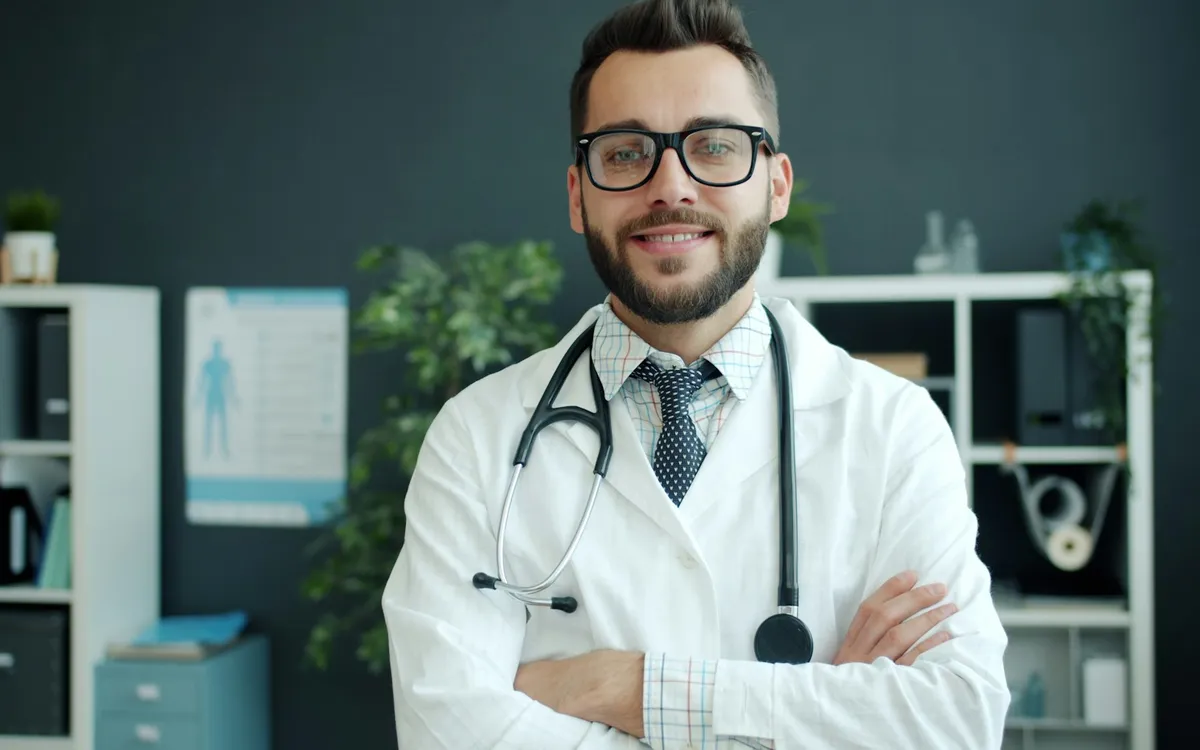 Médico sorridente de óculos com estetoscópio