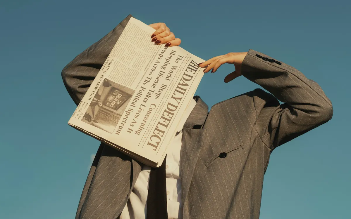 Pessoa de terno segurando um jornal aberto