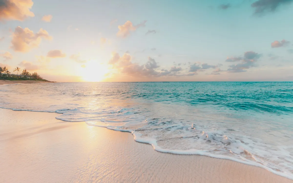Praia com mar calmo ao pôr do sol