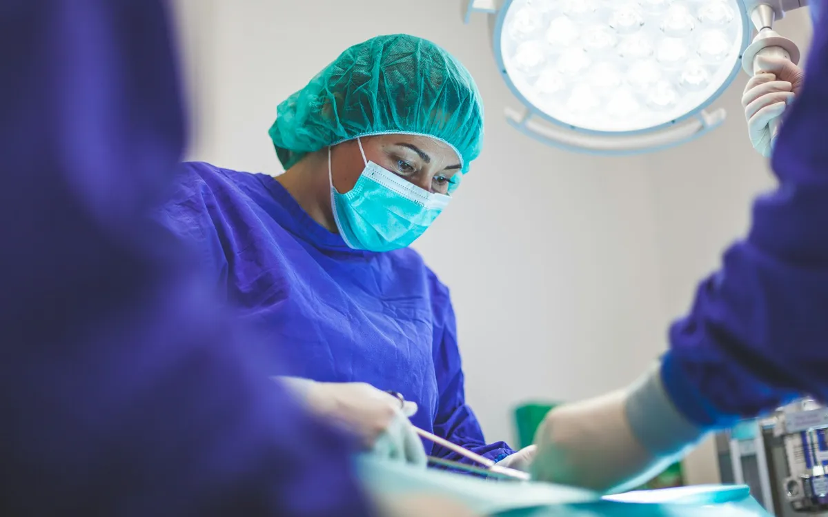 Cirurgiã com touca e máscara durante um procedimento