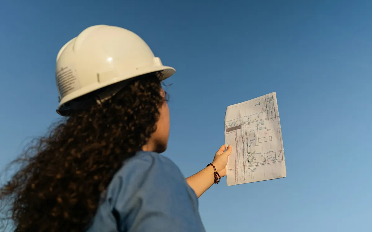 Engenheira de capacete conferindo um projeto em uma obra