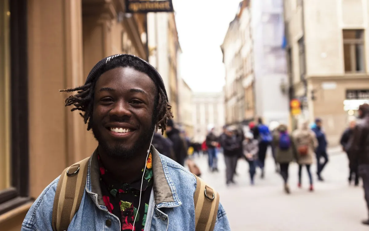Jovem sorrindo perto de um prédio na cidade