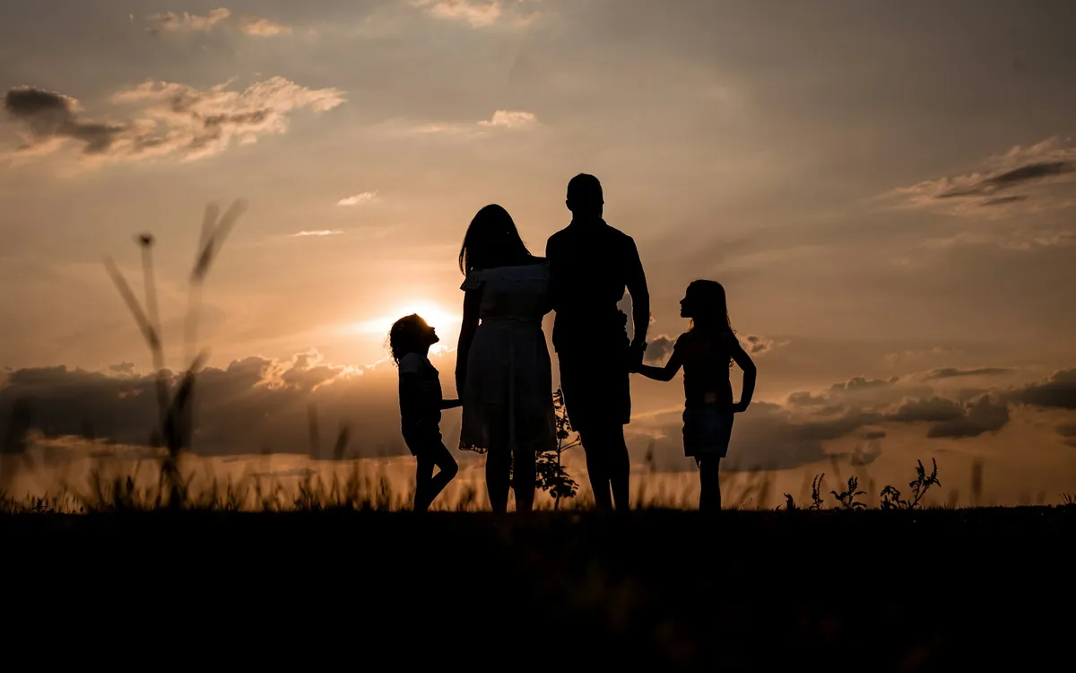 Família reunida em um campo ao pôr do sol