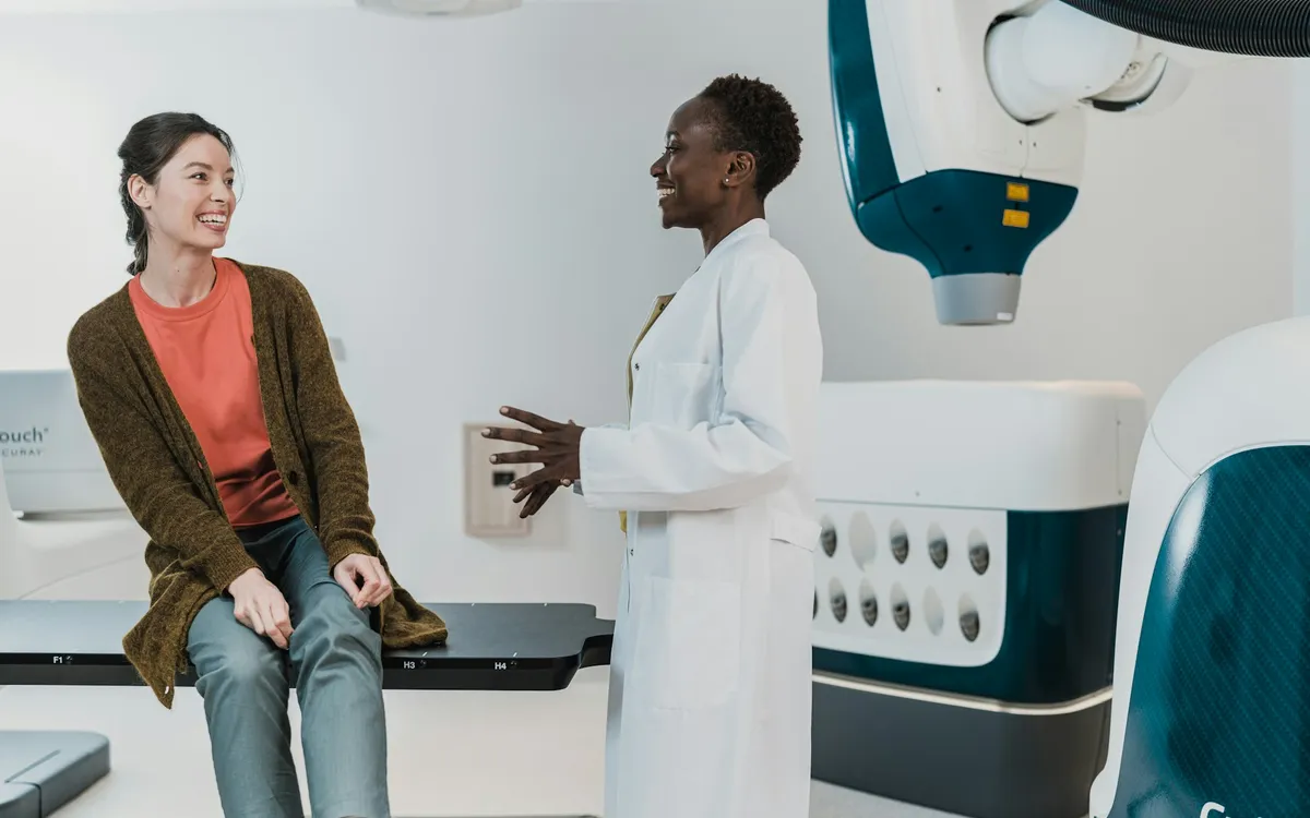Médico de jaleco conversando com um paciente no consultório