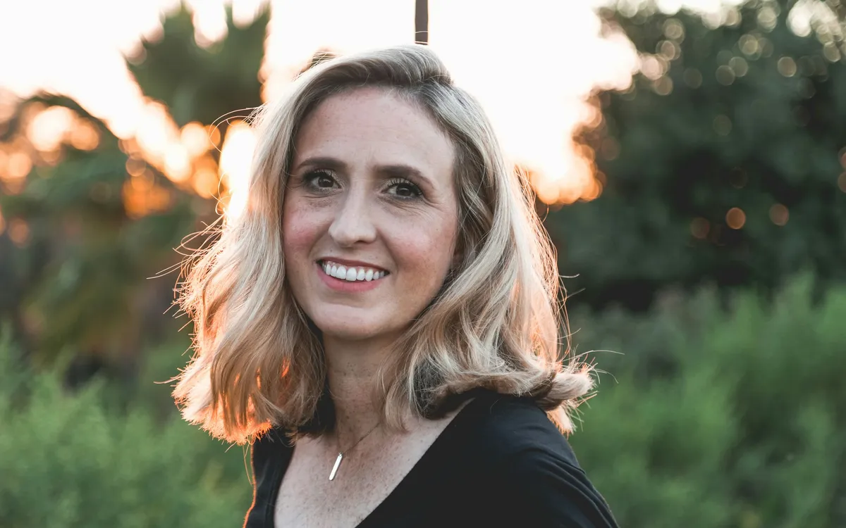 Mulher sorrindo ao ar livre com a luz do pôr do sol