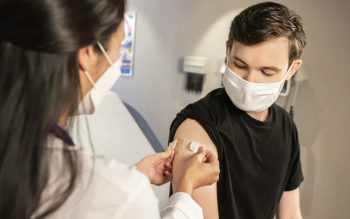 Profissional de saúde aplicando vacina no braço de um paciente