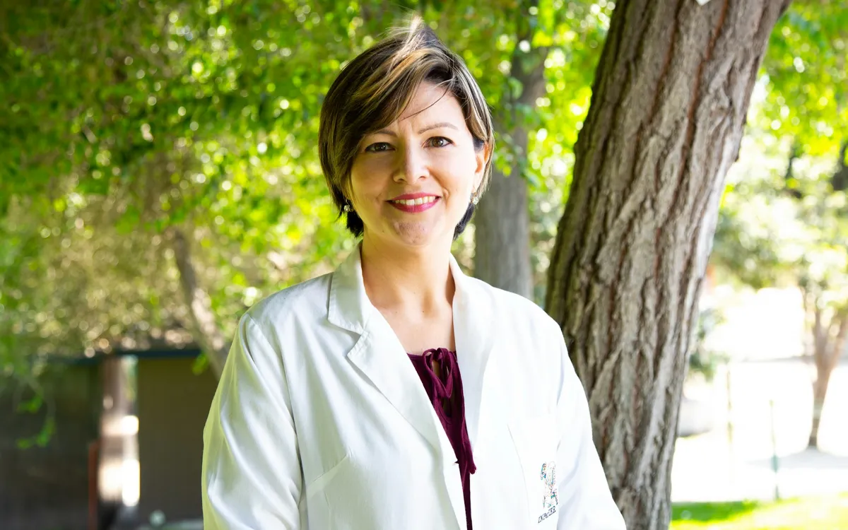 Médica de jaleco sorrindo ao ar livre